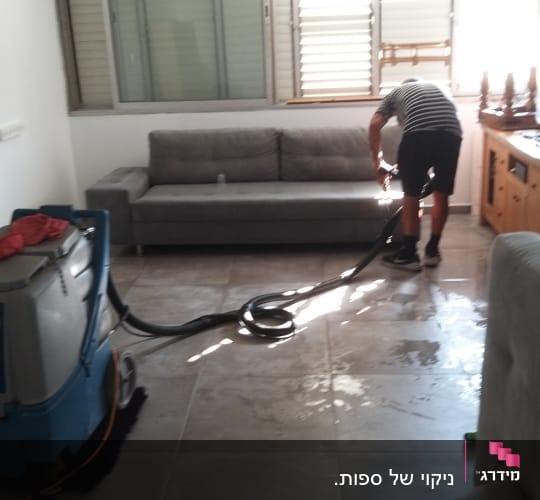 אדם מנקה ספה עם מכונת ניקוי מקצועית